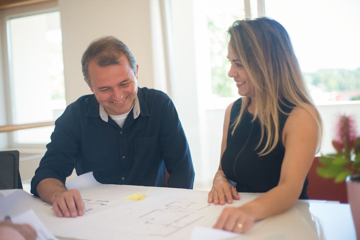 Couple smiling as they look through property paperwork together at a table